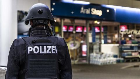 Ein Polizist sichert in den frühen Morgenstunden eine Tankstelle in Idar-Oberstein in Rheinland-Pfalz.