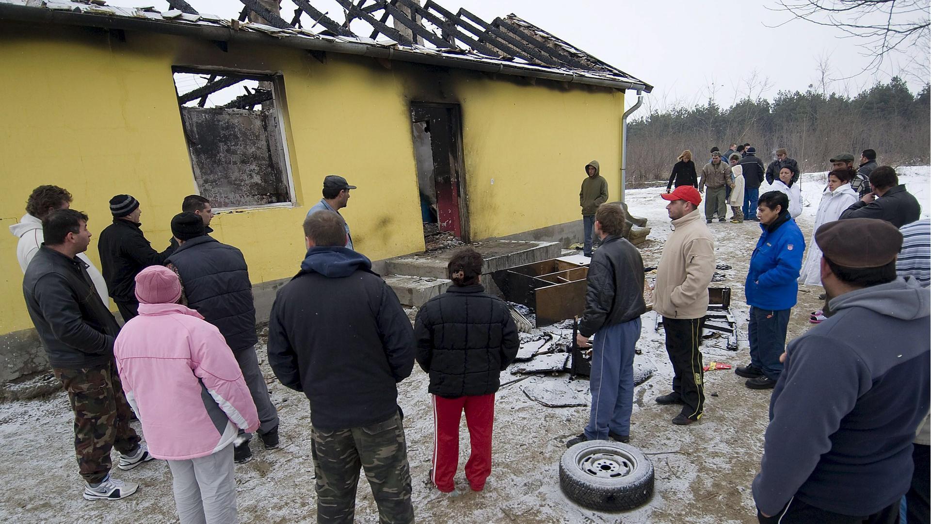 Picture made available on 24 February 2009 shows Romani people stand outside the ruins of a burnt-out family home at Tatarszentgyoergy, 55 kms southeast of Budapest, Hungary, 23 February 2009 after two bodies were found in the aftermath of a house fire. T Picture made available on 24 February 2009 shows Romani people stand outside the ruins of a burnt-out family home at Tatarszentgyoergy, 55 kms southeast of Budapest, Hungary, 23 February 2009 after two bodies were found in the aftermath of a house fire. T