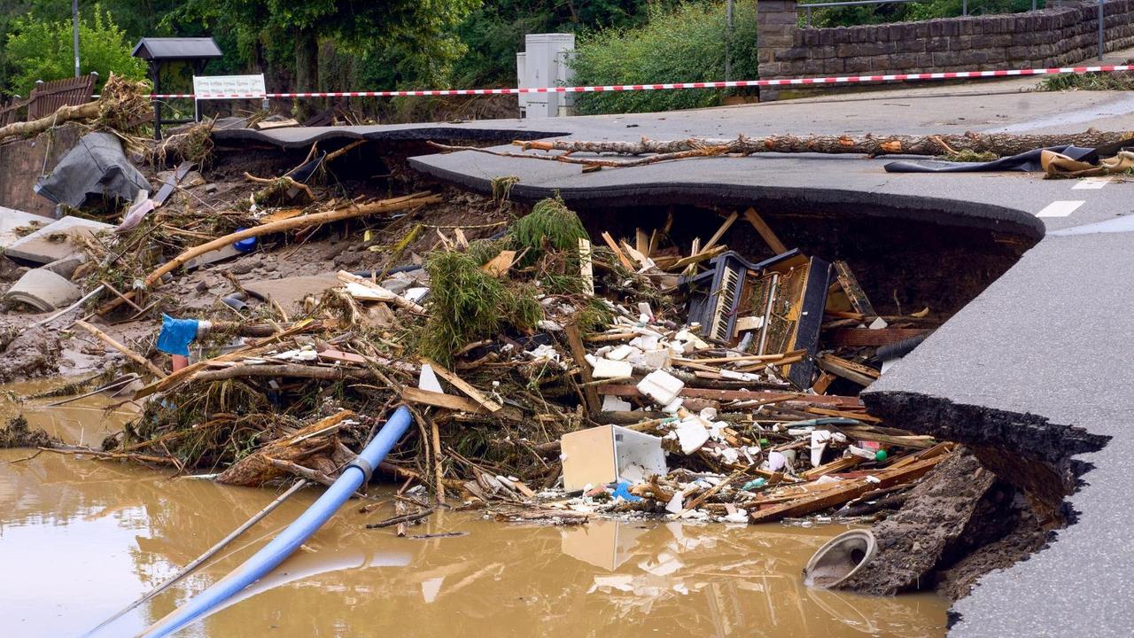 Ein Klavier liegt im Schutt unter einer unterspülten Straße im Kreis Ahrweiler am Tag nach dem Unwetter mit Hochwasser. Mindestens sechs Häuser wurden durch die Fluten zerstört.