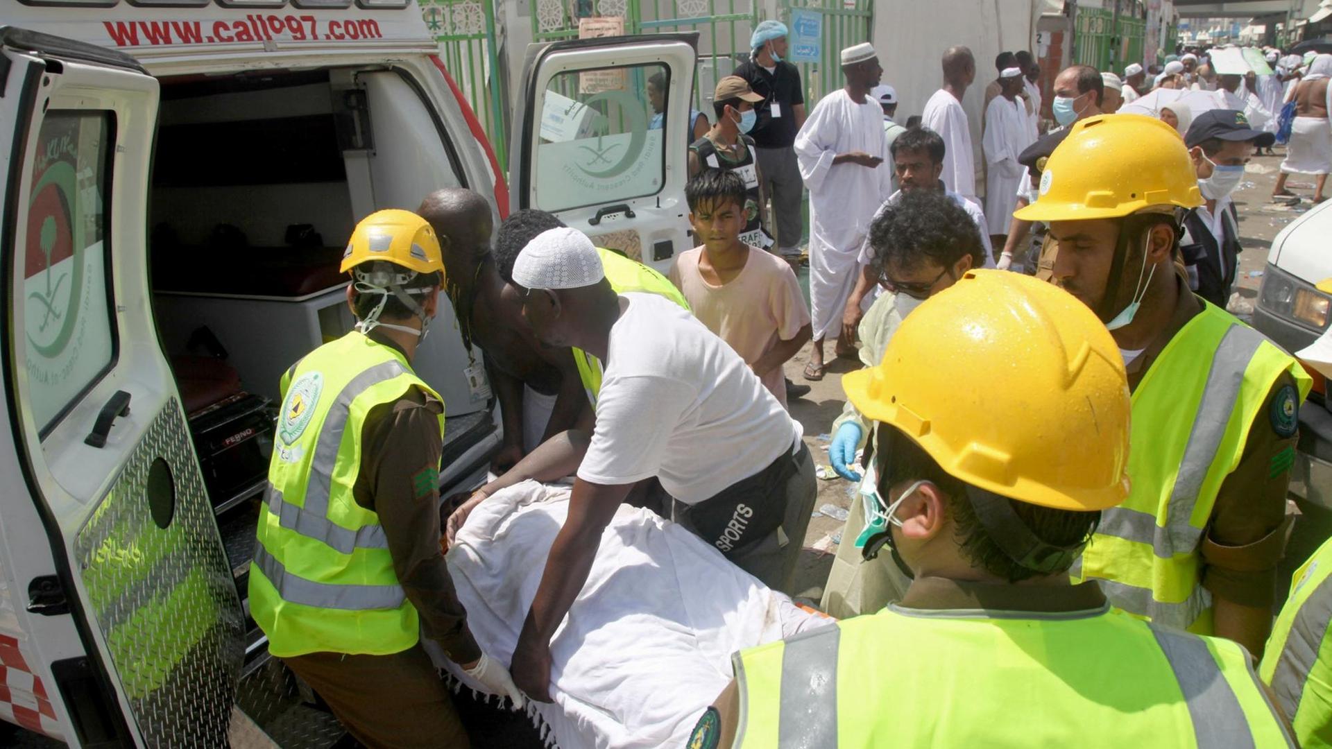 Sanitäter und weitere Helfer legen einen Verwundeten in einen Krankenwagen.
