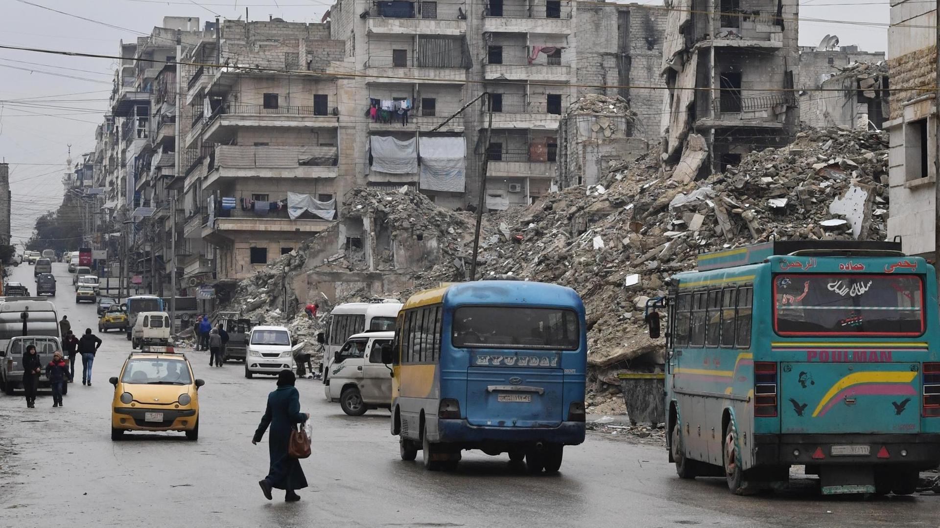 07.02.2019: Busse fahren auf einer Straße in Aleppo, zerstörte Häuser sind zu sehen