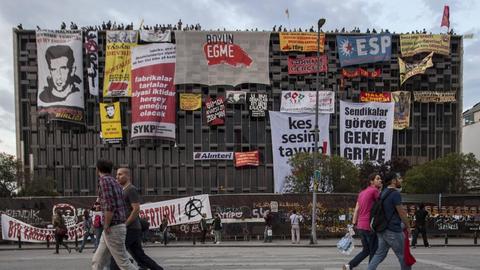 Menschen gehen am 04.06.2013 am Taksim Platz in Istanbul am leerstehenden und besetzten Opernhaus vorbei.