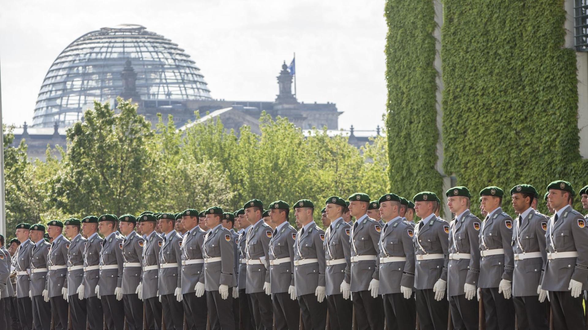 Bundeswehr-Soldaten stehen in einer Reihe, im Hintergrund ist die Reichstagskuppel in Berlin zu erkennen.