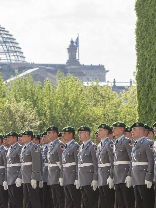 Bundeswehr-Soldaten stehen in einer Reihe, im Hintergrund ist die Reichstagskuppel in Berlin zu erkennen.