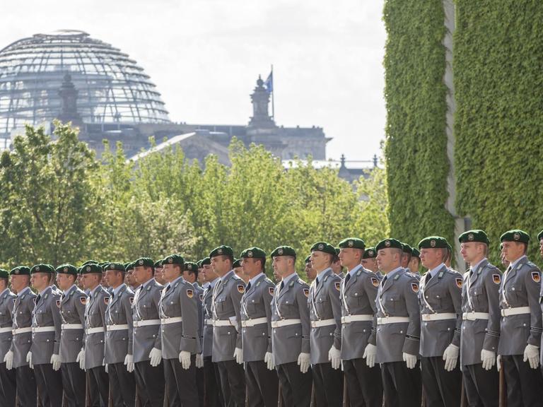 Bundeswehr-Soldaten stehen in einer Reihe, im Hintergrund ist die Reichstagskuppel in Berlin zu erkennen.