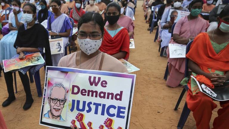Eine katholische Nonne (Mitte) mit einem Protestplakat fordert die Freilassung des Menschenrechtsaktivisten Stan Swamy bei einer Demonstration in Bengaluru, Indien, am 12. November 2020. Auf dem Plakat ist ein Bild Swamys abgedruckt mit dem Schriftzug "Wir fordern Gerechtigkeit".
