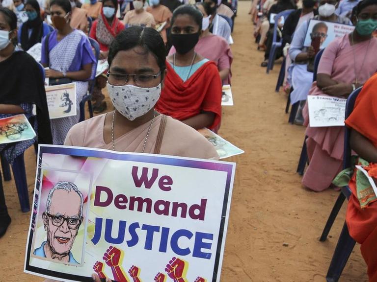 Eine katholische Nonne (Mitte) mit einem Protestplakat fordert die Freilassung des Menschenrechtsaktivisten Stan Swamy bei einer Demonstration in Bengaluru, Indien, am 12. November 2020. Auf dem Plakat ist ein Bild Swamys abgedruckt mit dem Schriftzug "Wir fordern Gerechtigkeit".
