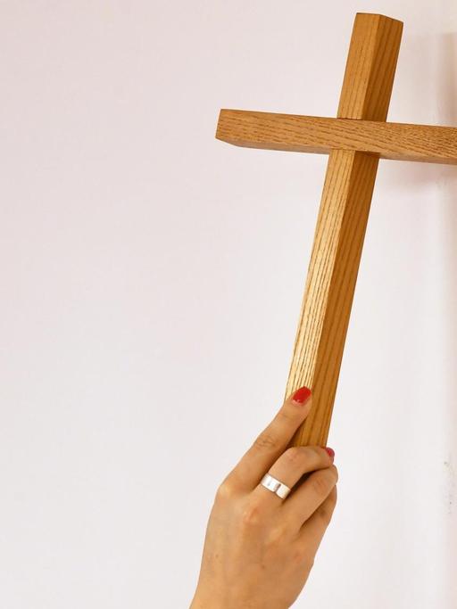Ein Kreuz wird an eine Wand gehängt.