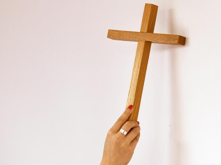 Ein Kreuz wird an eine Wand gehängt.