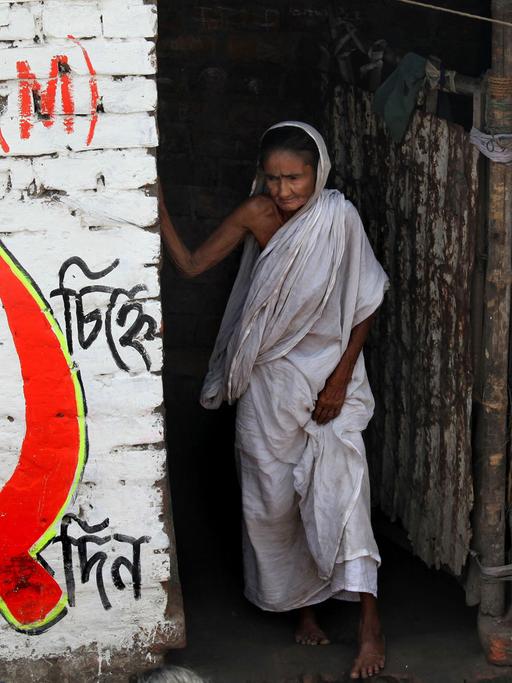 Eine ältere indische Frau steht im eingang ihres Hauses in Kalkutta/Kolkata.