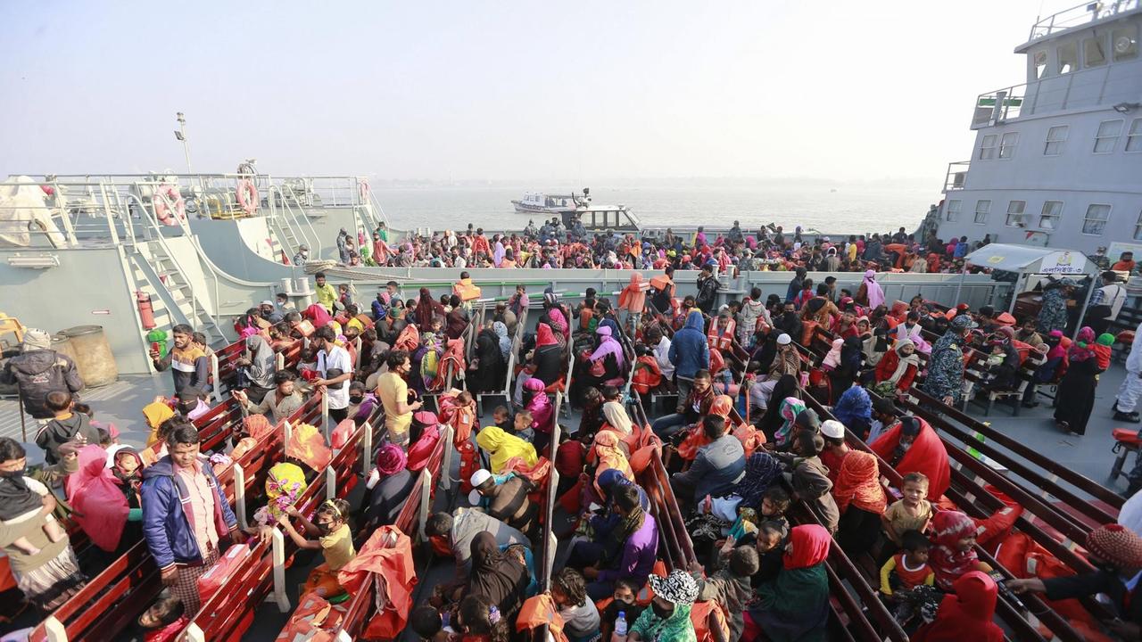 Rohingya in bunten Kleidern warten am Hafen von Chittatong (Bangladesch) auf einen Schiffstransport.