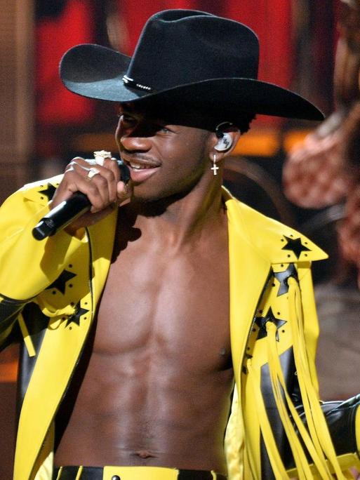 Rapper Lil Nas X singt mit schwarzem Cowboyhut und gelber Fransenjacke