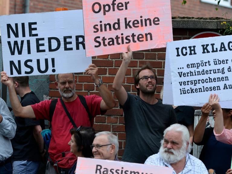 Teilnehmer einer Schweigeminute erinnern 2019 mit Plakaten auf der Kölner Keupstrasse am 15. Jahrestag an den NSU-Nagelbombenanschlag, bei dem dort 22 Menschen verletzt wurden, vier davon schwer. Am 9. Juni 2004 hatten