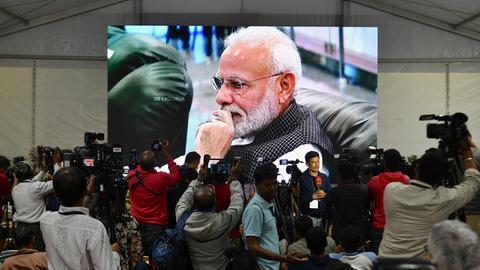 Indiens Premierminister Modi, zu sehen auf einer Leinwand, die in einem Zelt aufgestellt wurde. Davor Medienvertreter, welche die Landung der Mondsonde "Vikram" verfolgten.