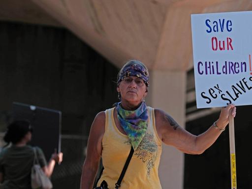Eine Frau hält ein Schild auf dem steht : Rettet unsere Kinder — Sexsklaven