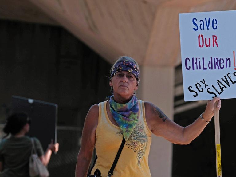 Eine Frau hält ein Schild auf dem steht : Rettet unsere Kinder — Sexsklaven