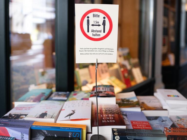 Ein Schild mit einem Hinweis auf die Abstandsregeln steht vor einer Buchhandlung in Hamburg.