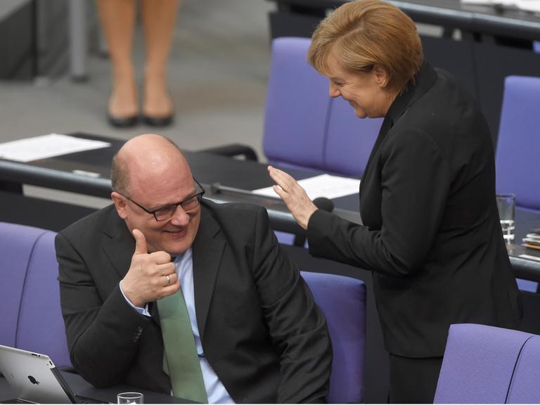 Bundeskanzlerin Angela Merkel (CDU, r) und Steffen Kampeter (CDU), Staatssekretär im Bundesfinanzministerium, im Bundestag. Beide lachen.