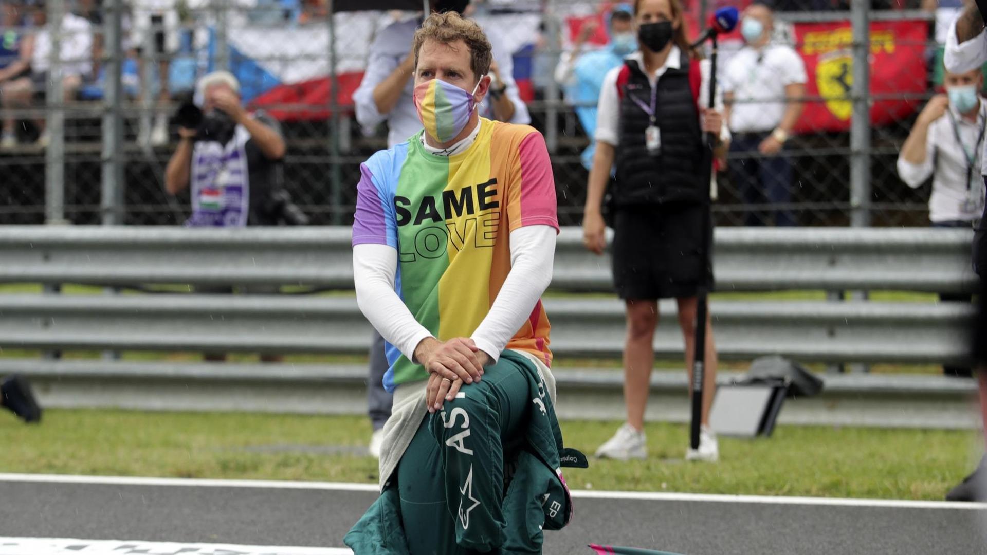 Ungarn, Mogyorod: Motorsport: Formel-1-Weltmeisterschaft, Großer Preis von Ungarn, Rennen: Sebastian Vettel aus Deutschland vom Team Aston-Martin kniet vor dem Rennen auf der Rennstrecke zur Unterstützung der Black-Lives-Matter-Bewegung nieder und trägt eine T-Shirt in Regenbogenfarben.