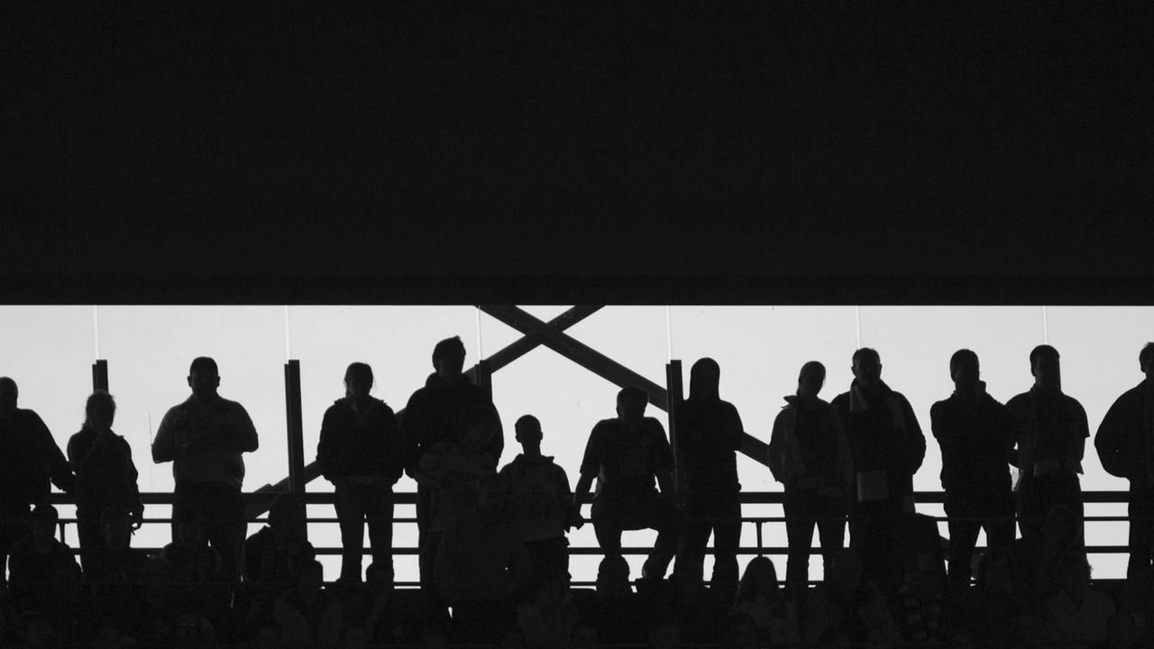 Die Umrisse von Fans auf der Tribüne bei einem Bundesligaspiel.