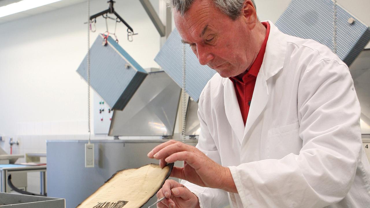 Günter Müller arbeitet in der Restaurierungswerkstatt für brandgeschädigtes Schriftgut in Weimar an teilweise verkohlten Bücherseiten.