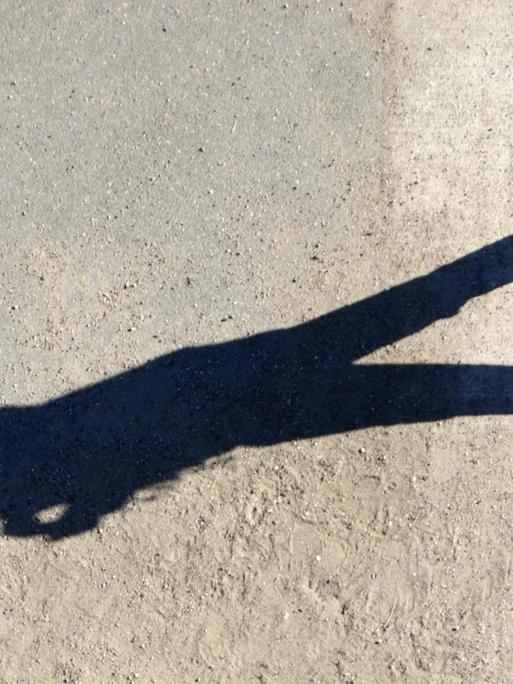 Der langgezogene Schatten einer Spaziergängerin.