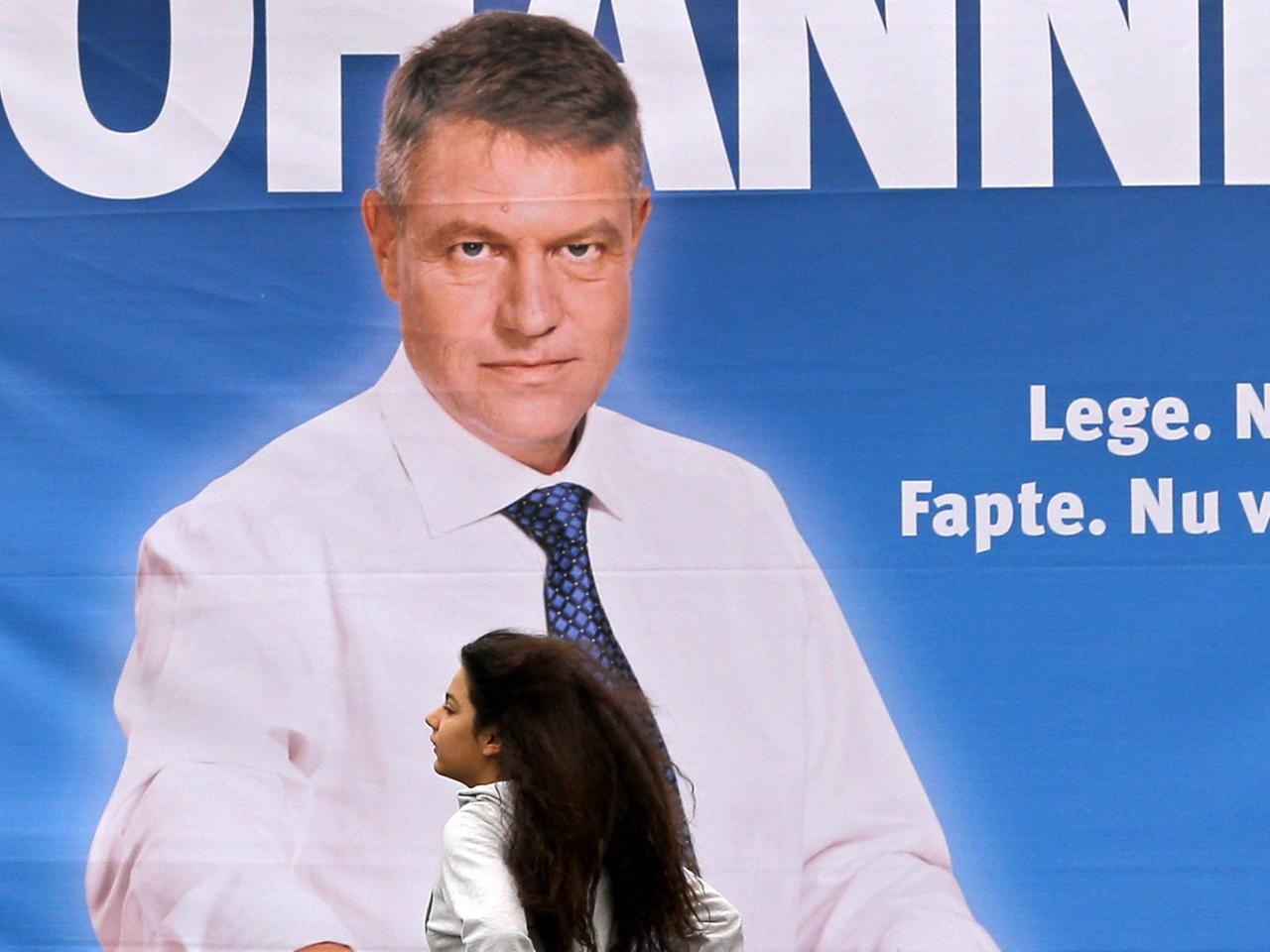 Eine Frau geht an einem Wahlplakat eines Kandidaten für die rumänische Präsientschaftswahl, Klaus Johannis, vorbei.