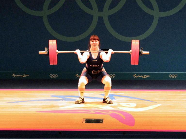 Die Gewichtheberin Swetlana Kabirowa steht auf einem Podest in der Hocke, sie drückte die Gewichte nach oben