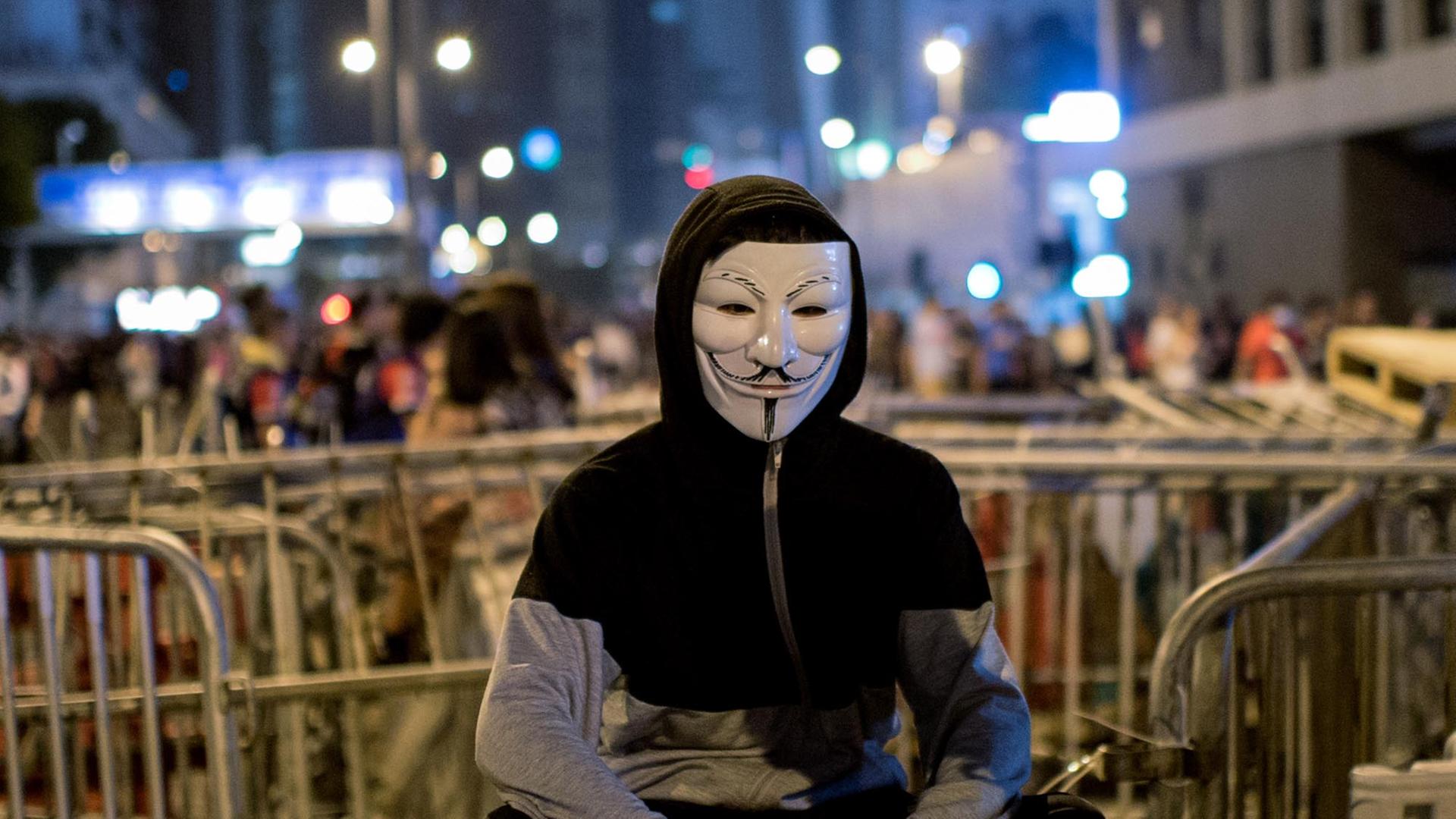 Ein Demonstrant mit Guy Fawkes Maske vor den Barrikaden der Demokratiebewegung in Hongkong.