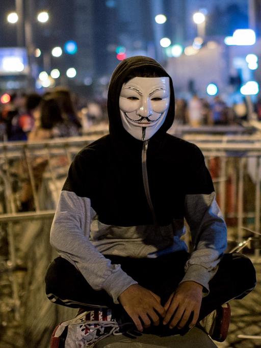 Ein Demonstrant mit Guy Fawkes Maske vor den Barrikaden der Demokratiebewegung in Hongkong.
