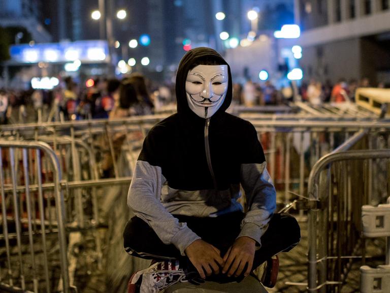 Ein Demonstrant mit Guy Fawkes Maske vor den Barrikaden der Demokratiebewegung in Hongkong.