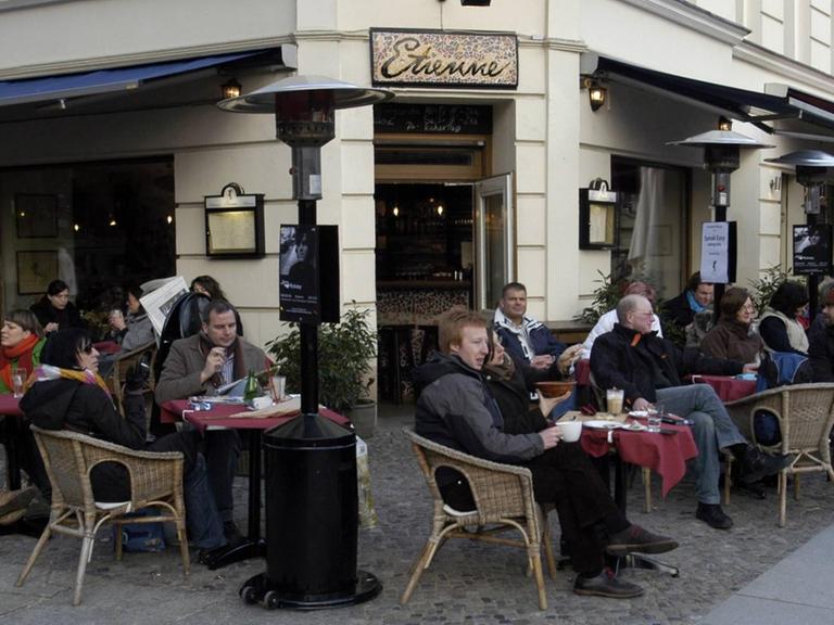 Gäste vor dem Restaurant - Etienne - am Kollwitzplatz in Berlin-Prenzlauer Berg. Sie sitzen an Tischen draußen vor dem Restaurant.
