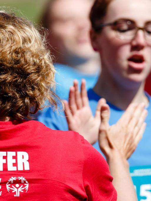 Eine Helferin (l) klatscht bei den Special Olympics, den nationalen Sommerspiele für Menschen mit geistiger oder mehrfacher Behinderung, mit der Athletin Vanessa Petry von der Friedrich-Joachim-Stengel-Schule in Heusweiler ab.