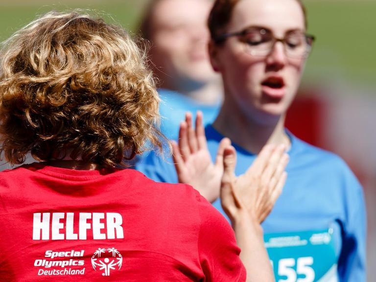 Eine Helferin (l) klatscht bei den Special Olympics, den nationalen Sommerspiele für Menschen mit geistiger oder mehrfacher Behinderung, mit der Athletin Vanessa Petry von der Friedrich-Joachim-Stengel-Schule in Heusweiler ab.