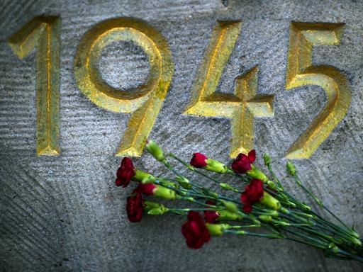 Vor der Jahreszahl "1945" auf einem Mahnmal auf dem Sowjetischen Garnisonfriedhof in Dresden (Sachsen) liegt ein Strauß roter Nelken.