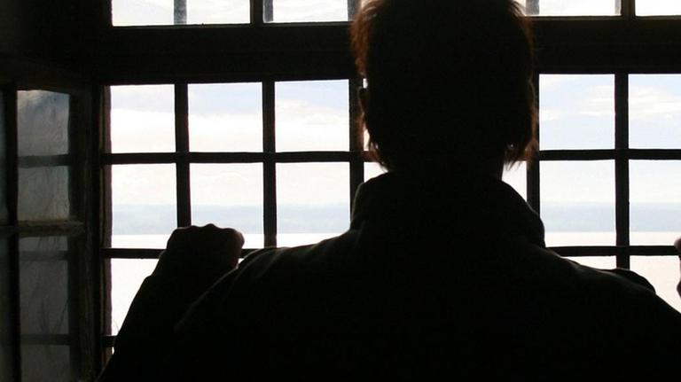Ein Mann im Gefängnis vor einem vergitterten Fenster