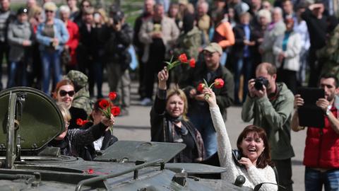 Frauen winken in der ukrainischen Stadt Slawjansk einem Panzer mit Blumen.