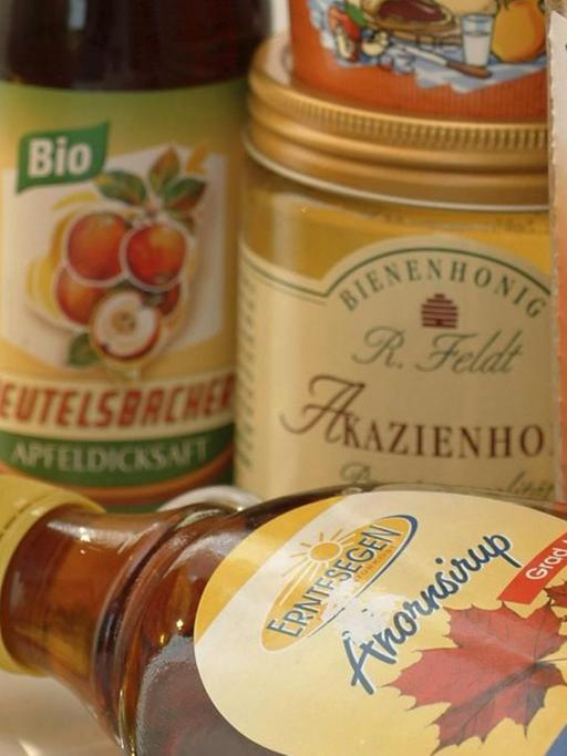 Alternative Süßungsmittel wie Ahornsirup, Agavendicksaft und Honig stehen zusammen auf einem Tisch