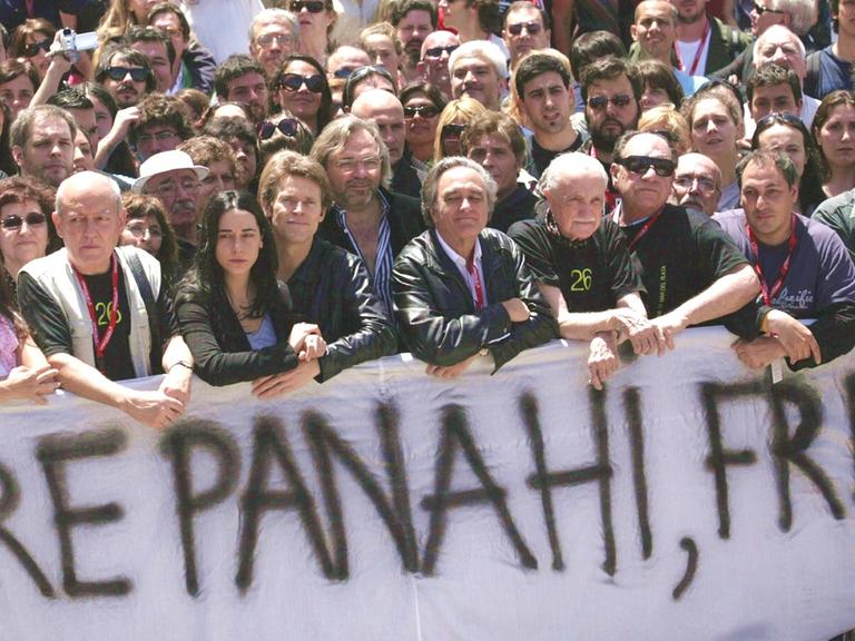 Aktivisten und Schauspieler demonstrieren für Jafar Panahi und halten ein Plakat hoch mit der Aufschrift "Freheit für Panahi".