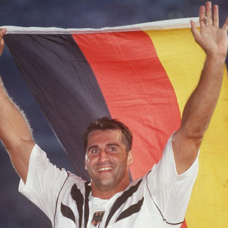 Diskuswerfer Lars Riedel, Gewinner der Goldmedaille, jubelt mit einer deutschen Flagge