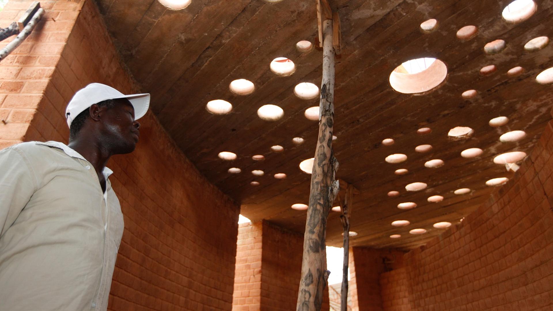 Der Architekt Francis Kéré begutachtet in dem burkinischen Dorf Gando den Baufortschritt an einem Bibliotheksgebäude.