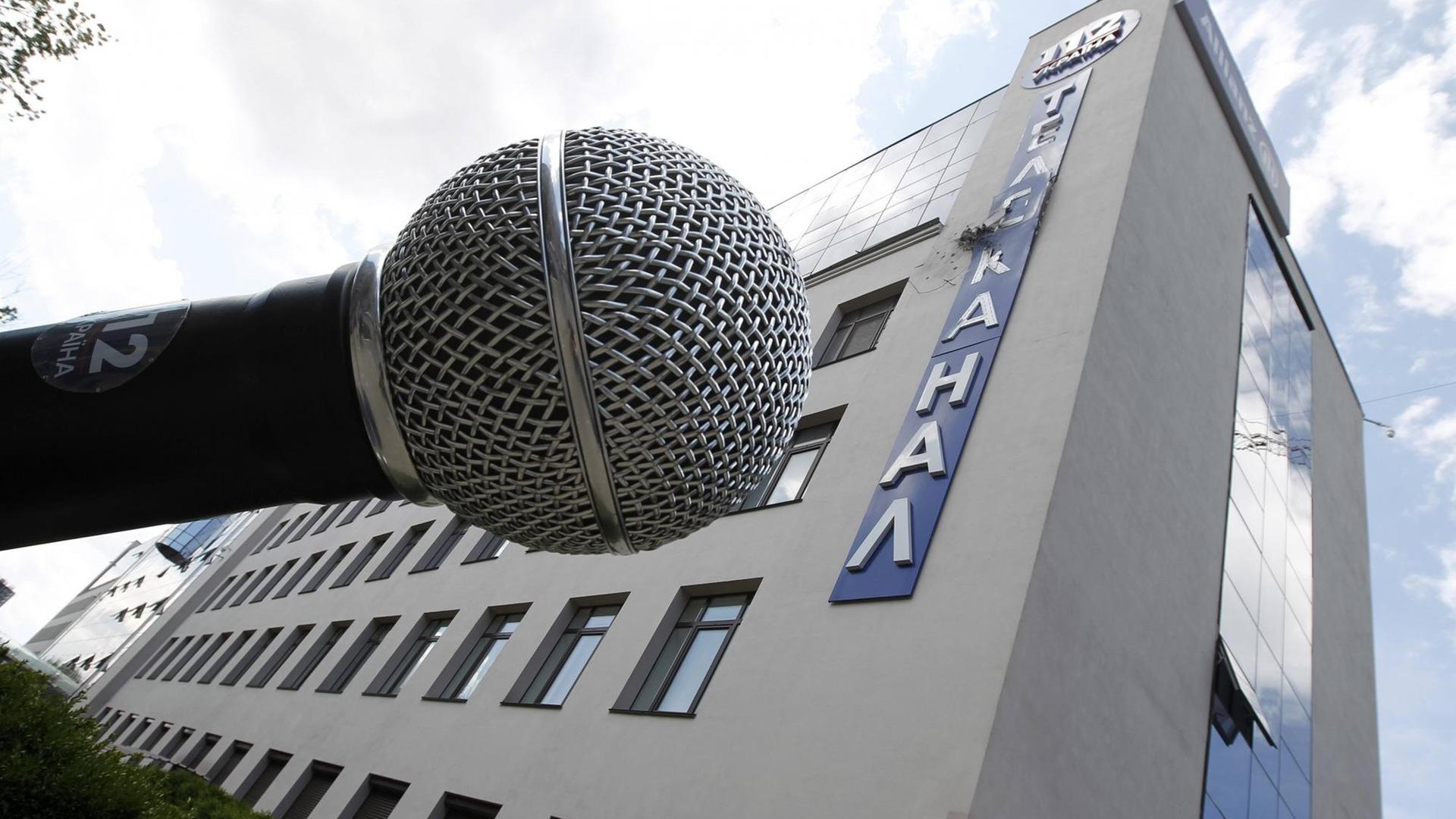 Vor dem Gebäude des ukrainischen Fernsehsenders "112" in Kiew steht ein überdimensionales Mikrofon. Der Schriftzug an der Fassade ist durch einen Angriff zerstört.