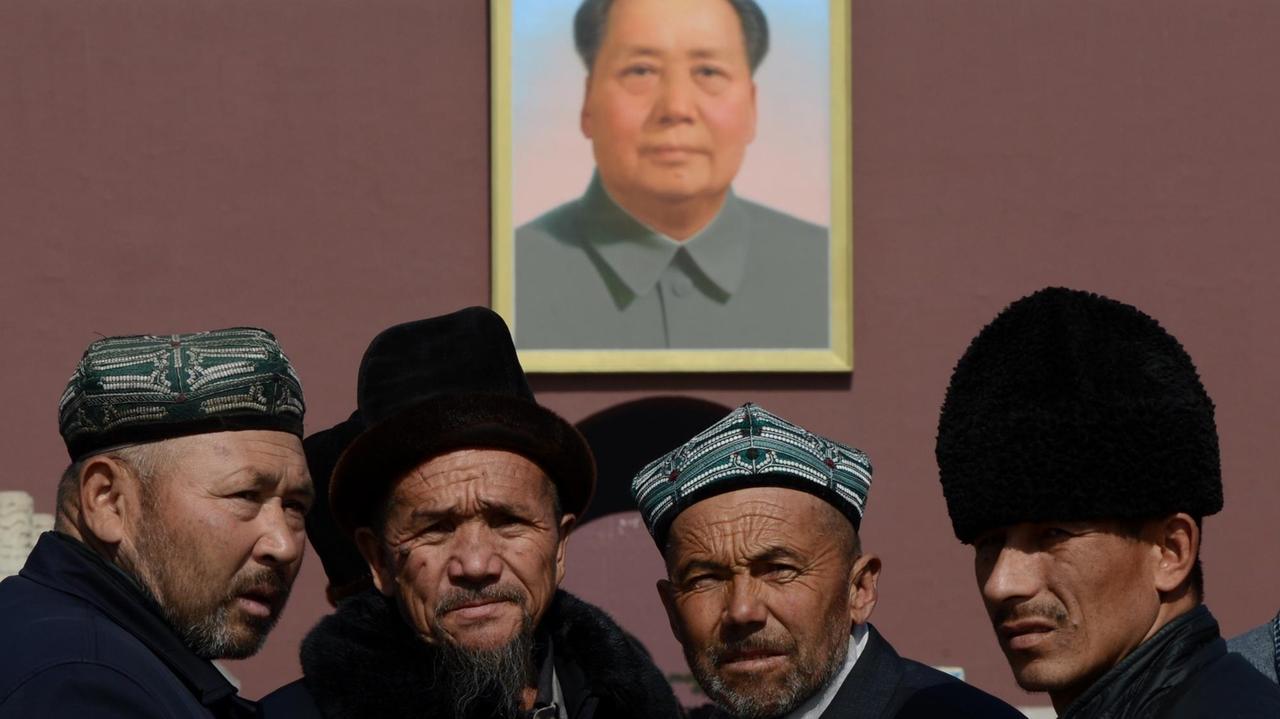 Eine Delegation traditionell gekleideter Uiguren aus der Provinz Xinjiang posiert vor Beginn des chinesischen Volkskongress 2013 unter dem Mao-Bildnis über dem Tor des Himmlischen Friedens in Peking.