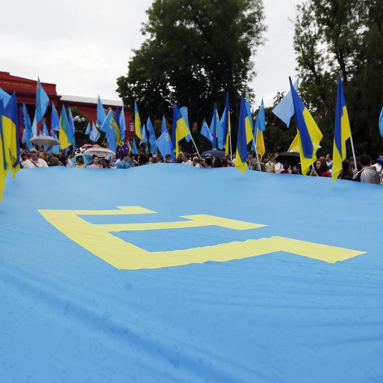Menschen halten eine Flagge der Krimtataren in Händen. Sie erinnern in Kiew an den 70. Jahrestag der Krim-tatarischen Deportation. (Archivbild 2014)

