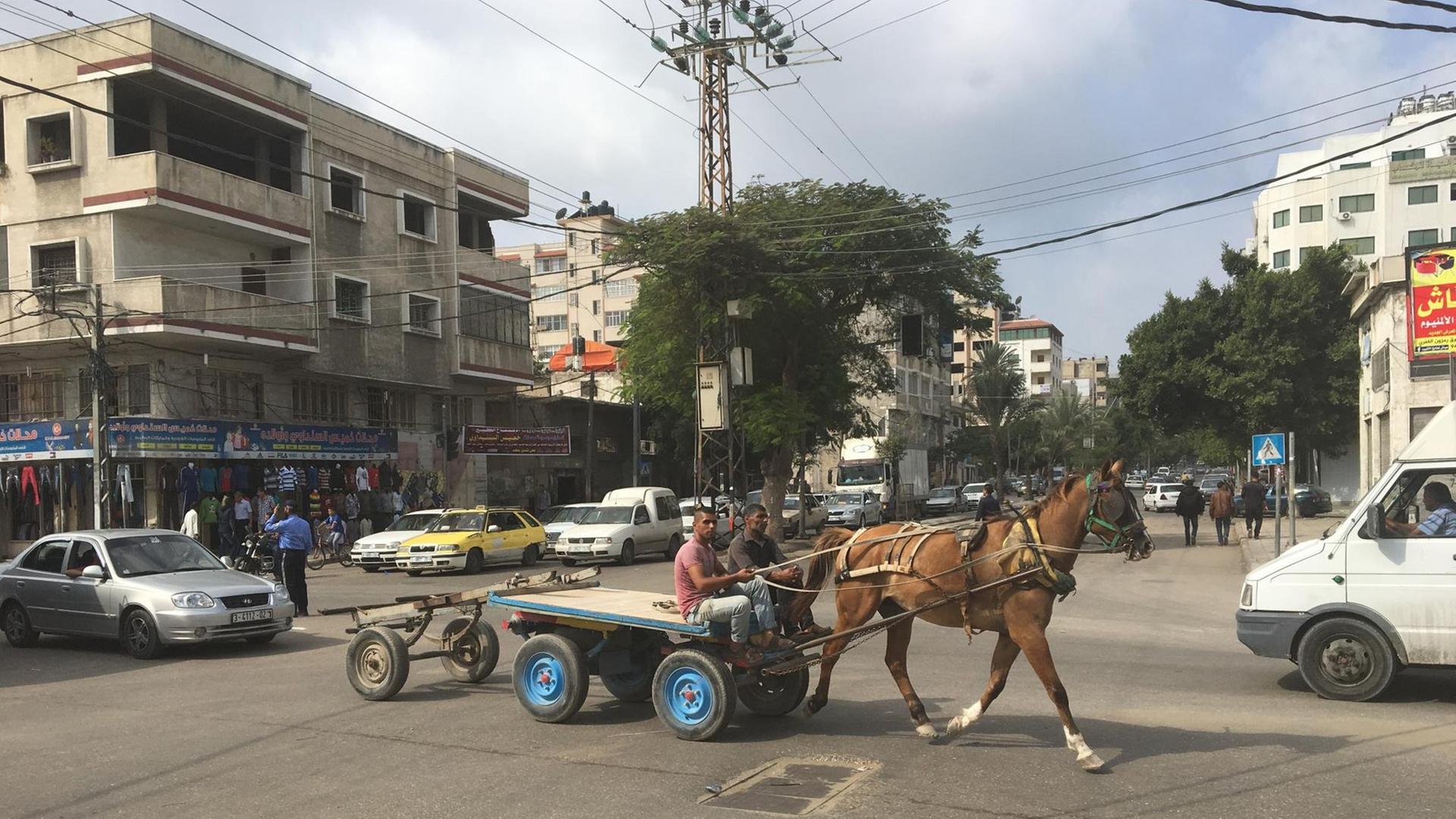 Ein Pferdegespann mit zwei jungen Menschen überquert eine Verkehrskreuzung in Gaza-Innenstadt.