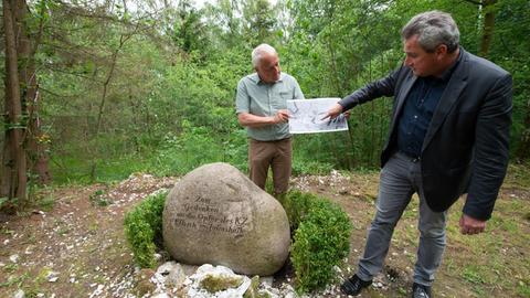 Niedersachsen, Walkenried: Jens-Christian Wagner (r), Geschäftsführer der Stiftung niedersächsische Gedenkstätten, und Henning Haßmann, Landesarchäologe vom niedersächsischen Landesamt für Denkmalpflege, stehen mit einer hochauflösende Abbildung der Geländeoberfläche neben einem Gedenkstein vor dem Fundort des Sammelgrabes. Das ehemalige Konzentrationslager an der Grenze zwischen Niedersachsen und Thüringen war das größte Außenlager des KZ Mittelbau-Dora.