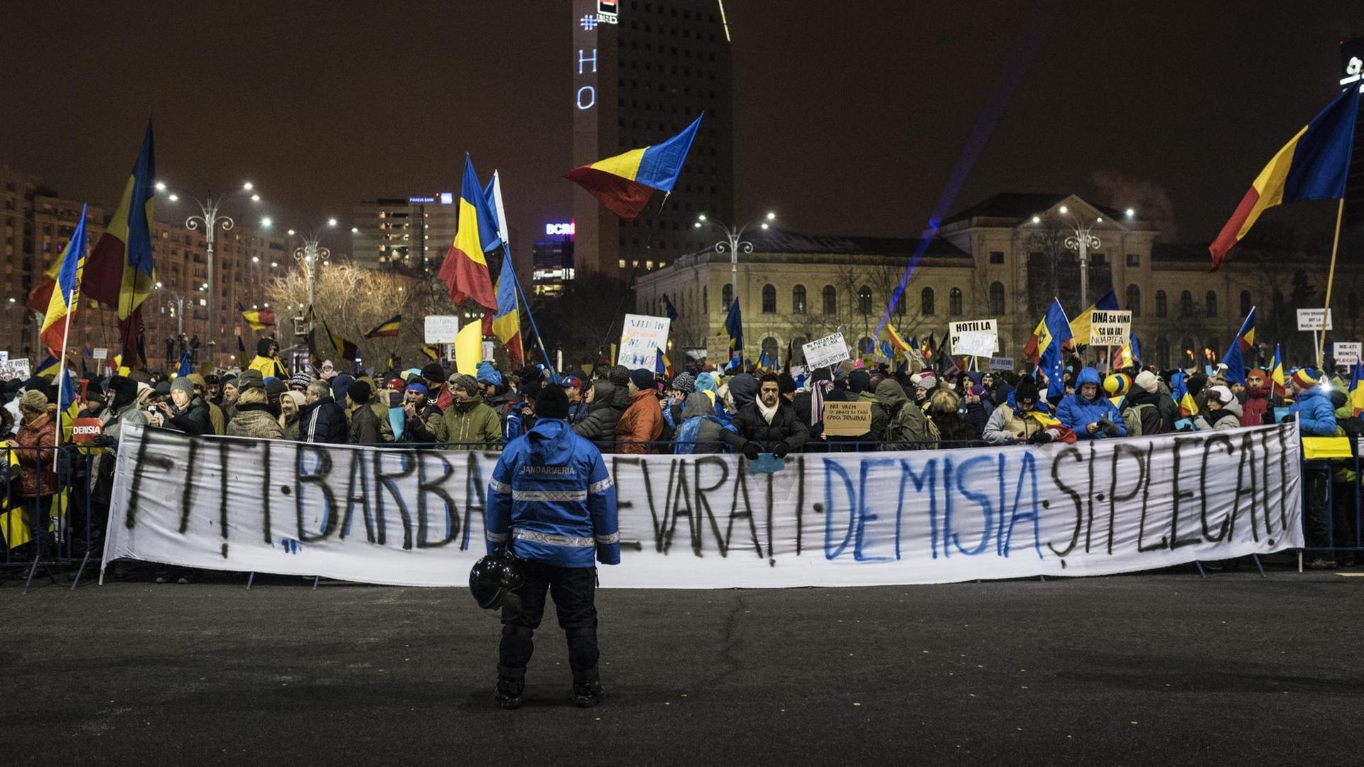 Demonstranten halten auf dem Siegesplatz in Bukarest Flaggen und Protestplakate. AUfnahme vom 12. Februar 2017.