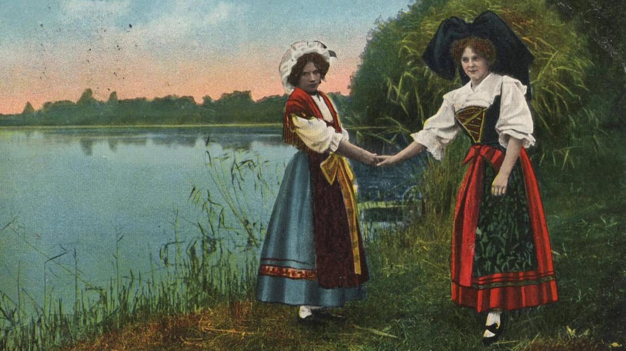 Eine Elsässerin und eine Lothringerin auf einer historischen Fotopostkarte, koloriert um 1910.