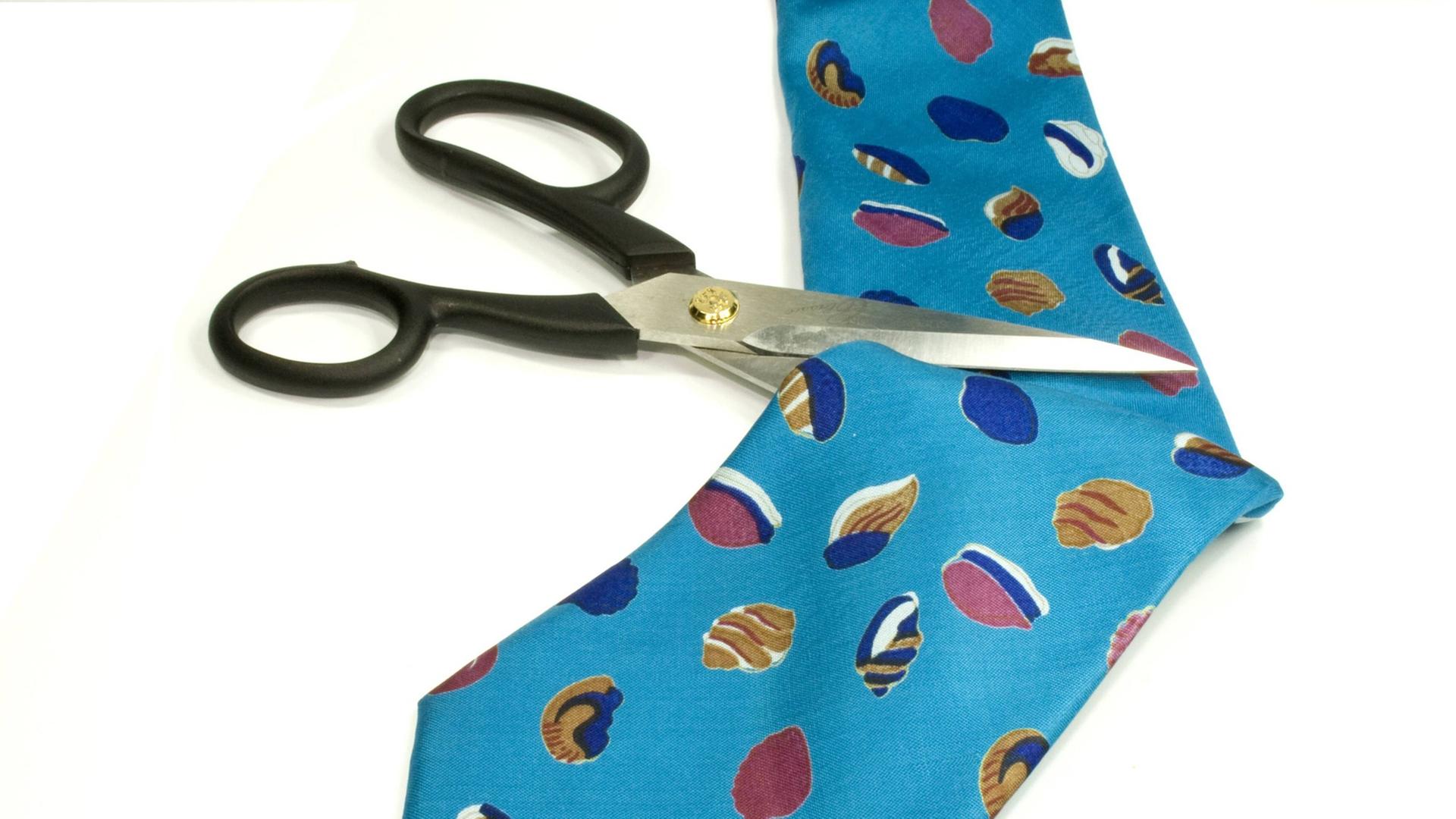 Eine Schere setzt zum Schnitt an einer Krawatte an.
