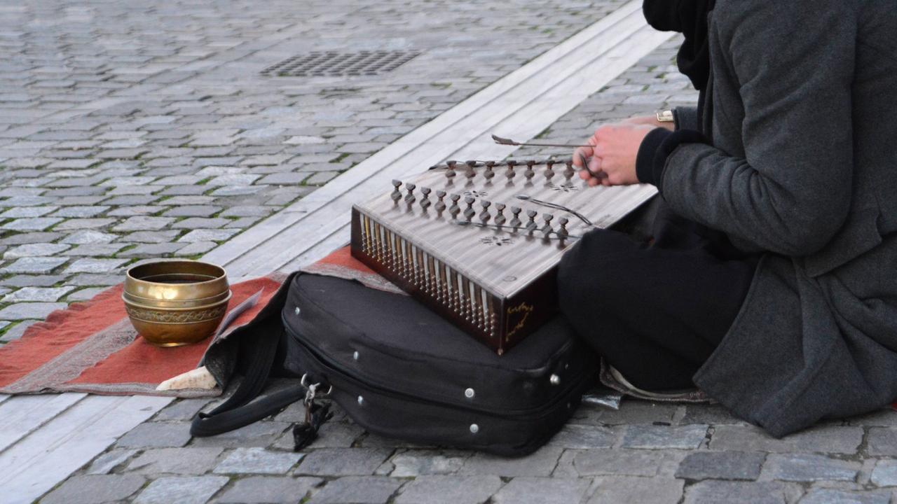 Ein junger Straßenmusikant in Athen spielt Santur, ein persisches Musikinstrument
